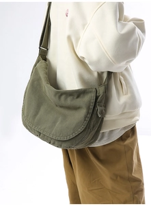 Side view of an army green canvas messenger bag with functional cargo pocket and metal buckle