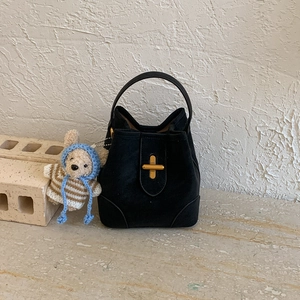 Détail du sac seau noir en daim avec fermoir doré en croix et charm ours mignon