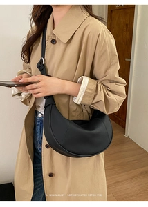 Chic black crescent hobo bag with adjustable strap styled with a minimalist trench coat