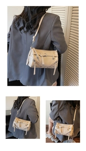 Detail view of beige underarm bag with decorative zippers and adjustable strap accents