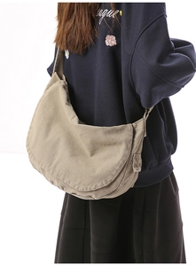 Side view of large khaki canvas messenger bag showing adjustable strap and pocket detail
