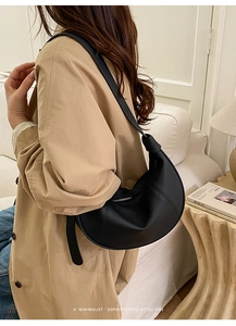 Detail of minimalist black crescent faux leather shoulder bag with adjustable wide strap