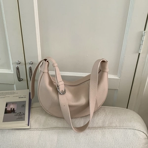 Detail of lychee pattern leather on beige-pink crescent shoulder bag with silver hardware