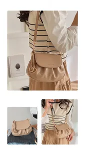 Détail du sac selle beige clair avec fond plissé et finitions métalliques dorées