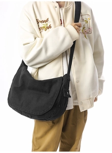Detail of black canvas messenger bag featuring side snap pocket and durable wide strap