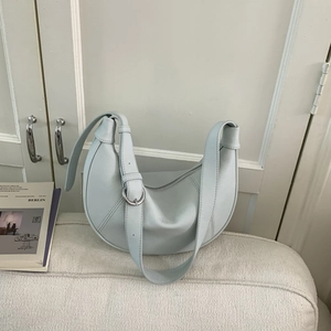 Close-up of light blue crescent saddle bag with litchi texture and silver buckle detail