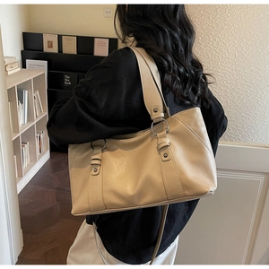 Close-up of beige leather tote bag with silver ring buckles and stylish shoulder strap