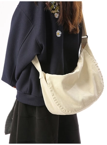 Close-up of beige canvas messenger bag with wide adjustable shoulder strap detail