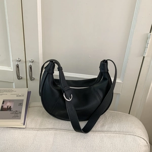 Detail of minimalist black hobo bag with adjustable wide strap and silver metal buckle