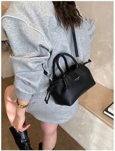 Détail d'un sac cabas noir en cuir grainé avec bandoulière et cordon de serrage latéral