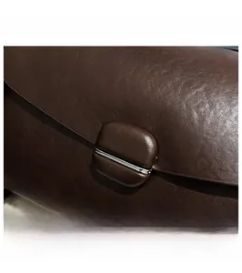 Macro shot of dark brown pebbled leather texture and silver buckle detail on handbag