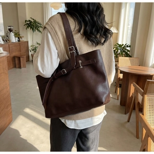 Détail des boucles argentées sur un grand sac cabas vintage marron foncé porté