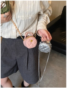 Détail du mini sac rond matelassé avec fleur dorée et bandoulière en chaîne