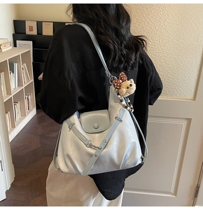 Detail der hellblauen glänzenden PU-Tasche mit Metallschnallen und Plüschbär-Anhänger
