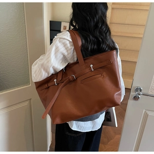 Détail du sac cabas marron vintage montrant la boucle en métal et les coutures de côté