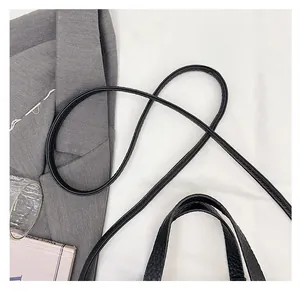 Détail du sac seau noir en cuir à grain de litchi avec de fines bretelles et poignée