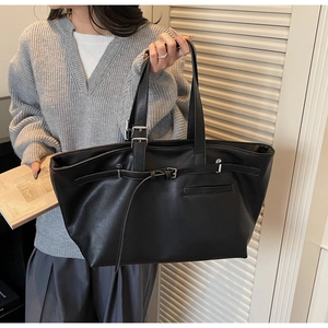 Détail d'un grand sac cabas noir vintage avec bandoulière réglable et finition cuir mat