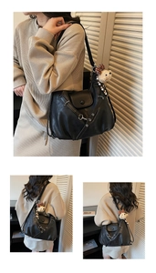 Detail der schwarzen Tote-Tasche mit Falten, beigem Plüschbär-Anhänger und weichem Leder