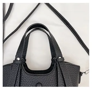 Détail des poignées du sac seau en cuir noir grainé avec des rivets argentés polis