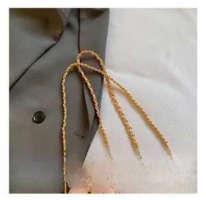 Détail d'un sac à main rose matelassé avec bandoulière en chaîne dorée entrelacée de cuir