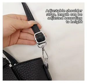 Détail de la bandoulière réglable noire à texture litchi avec boucle argentée pour sac seau