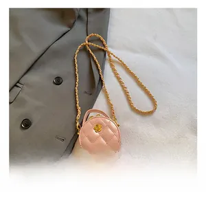 Vue macro d'un mini sac matelassé rose clair avec emblème floral doré chic