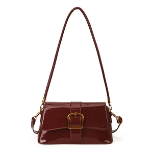 Nahaufnahme der glänzenden burgunderroten Lackledertasche mit goldener Metallschnalle