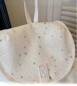Vue détaillée du sac à dos en toile crème avec motifs d'étoiles argentées et petits pois