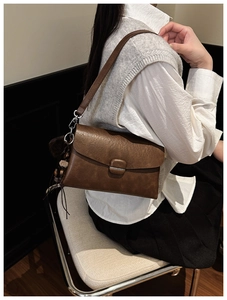 Close-up of deep brown vintage envelope bag with a textured finish and decorative charms
