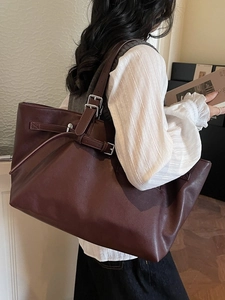 Grand sac cabas vintage en cuir marron foncé avec boucle argentée porté par un modèle