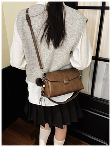 Detail of vintage brown leather crossbody bag with decorative bead and fur ball charms