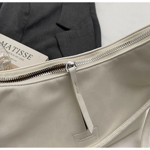 Détail d'un sac sous les bras en similicuir blanc avec fermeture éclair argentée