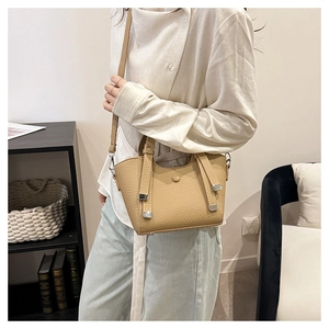 Détail d'un sac seau en cuir beige avec poignées et fine bandoulière pour un look chic