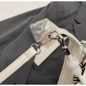 Détail des crochets en métal argenté et perles blanches sur un sac en cuir chic