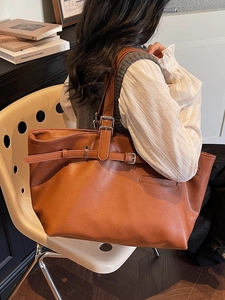 Grand sac fourre-tout vintage en cuir marron exposé sur une chaise blanche pour le quotidien