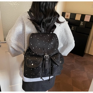 Detail of black backpack with silver star print featuring metal buckles and pocket flaps
