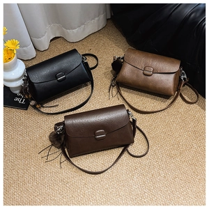 Minimalist square crossbody bags in black and brown leather with cute pom-pom charms