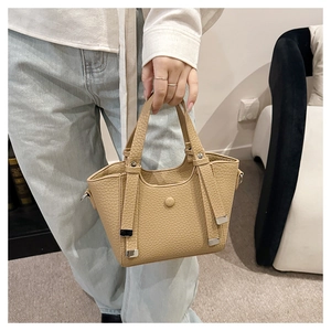 Détail du sac seau en cuir grainé marron clair avec des coins en métal argenté élégants