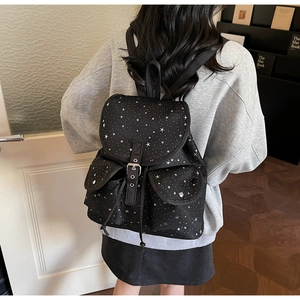 Détail du sac à dos noir à imprimé étoiles avec deux poches et rabat à boucle