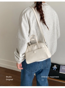 Detailed side view of beige PU leather bucket bag worn as a casual crossbody messenger bag