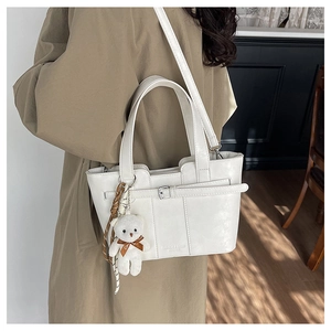 Lifestyle view of a white leather bucket bag with cute bear charm and shoulder strap