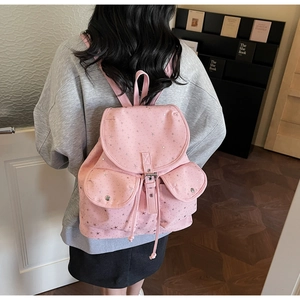 Detail view of a pink canvas backpack with silver star patterns and drawstring closure