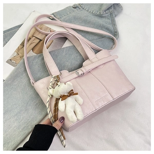 Detail of light pink bucket bag with leather strap and white plush bear keychain charm