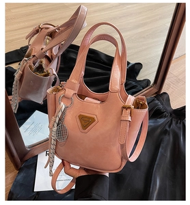 Détail du sac seau rose avec plaque logo triangulaire et breloque de raquette de tennis