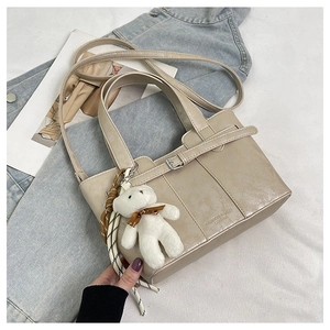 Close-up of cream bucket bag with bear charm on denim jacket background detail