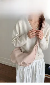 Nahaufnahme einer blassrosa gefalteten Cloud-Tasche am Modell mit weicher Lederoptik