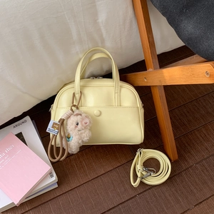 Detail of yellow leather Boston bag with a cute sheep charm and adjustable strap