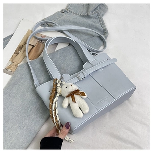Detail of light blue bucket bag with leather texture and white plush bear charm