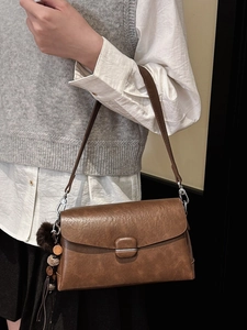 Retro brown textured shoulder bag with tassel charm and square buckle, shown on model