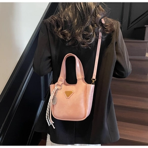 Détail du sac à main rose avec logo triangulaire en métal et pendentif en corde tressée